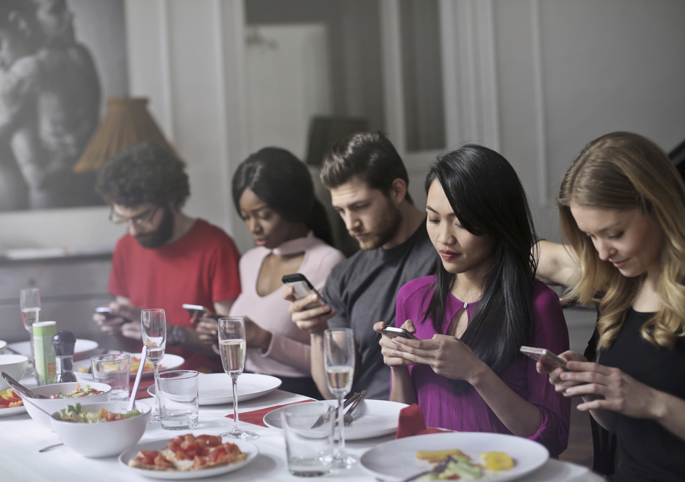 dinner party of people all on their phones, distracted